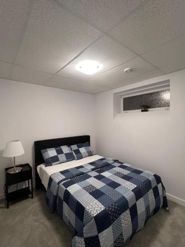 温尼伯Well furnished 1 Bedroom Basement Suite的一间卧室配有一张带蓝白色 ⁇ 面毯的床