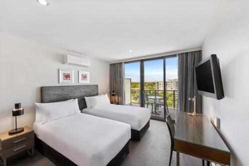 堪培拉Adina Serviced Apartments Canberra Dickson的酒店客房配有两张床和一张书桌