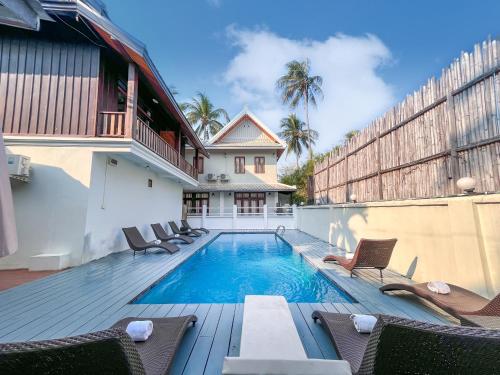 琅勃拉邦绿洲别墅酒店的一个带椅子的游泳池以及一座房子