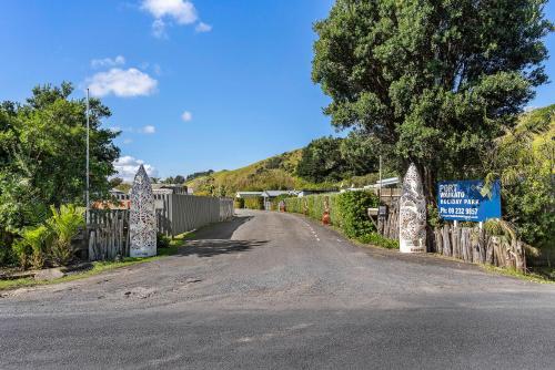 Port Waikato怀卡托港假日公园的山坡上一条有栅栏和标志的道路