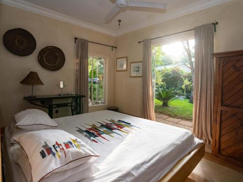 维多利亚瀑布The Art House Victoria Falls的一间卧室配有一张带色彩缤纷枕头的床和窗户。