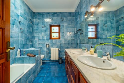 圣塔格鲁迪斯Villa Can Joan den Coves的蓝色瓷砖浴室设有浴缸和水槽