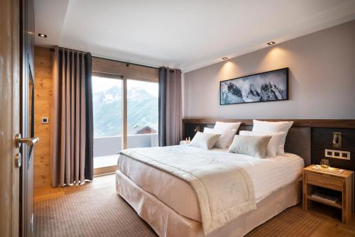 拉赫兹耶尔Hôtel Alpen Lodge的一间卧室设有一张大床和一个大窗户