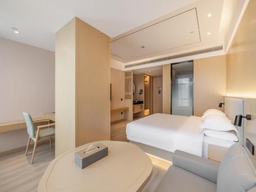 杭州无眠杭州大江东海德新港中心酒店的卧室配有白色的床、书桌和桌子