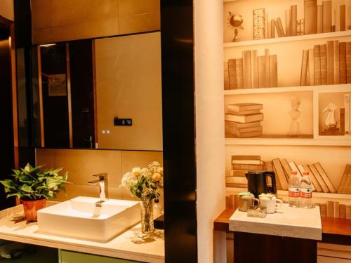 亳州格美安徽省亳州市亳州学院酒店的一间带水槽、镜子和书籍的浴室