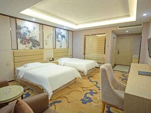 宜春格菲宜春市袁州区政府高铁站酒店的酒店客房带两张床和一张桌子以及椅子。