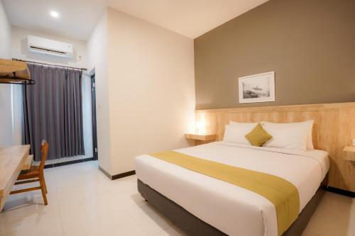 纳闽巴霍El Ora Hotel & Eatery Labuan Bajo的配有一张床、一张书桌和一扇窗户的酒店客房