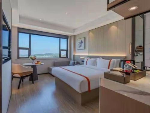 武汉格林东方武汉光谷东湖武汉大学酒店的酒店客房设有一张大床和一张桌子。