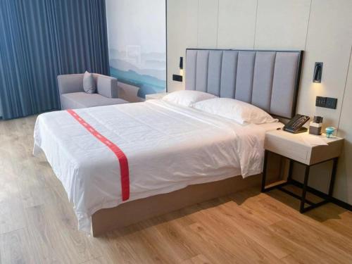 Xiaosongzhuang格林东方阜阳界首市火车站新阳东路酒店的一间卧室配有一张大床,桌子上配有电话