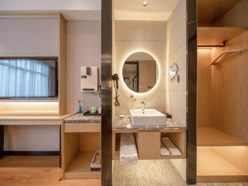 阜阳格菲阜阳市火车站北京东路酒店的浴室的两张照片,配有水槽和镜子
