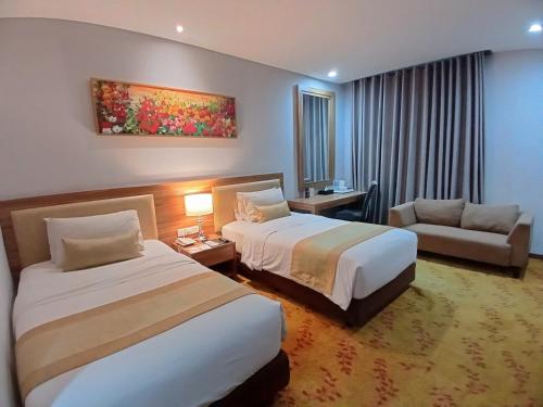日惹Grand Serela Yogyakarta by KAGUM Hotels的酒店客房,设有两张床和一张沙发