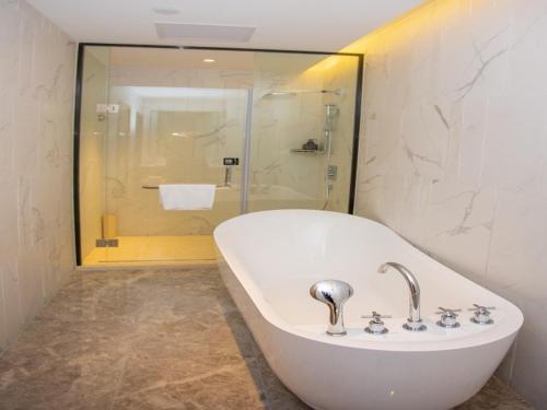 滨州格林东方滨州市中海·国际会展中心酒店的带淋浴的浴室配有白色浴缸。