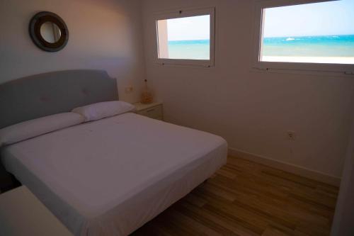 托雷德尔马尔Hostal Paraiso del Mar的卧室配有白色的床和2扇窗户。