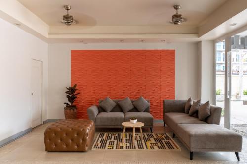 芭堤雅市中心Heeton Concept Hotel Pattaya by Compass Hospitality的客厅设有两张沙发和一堵红色的墙