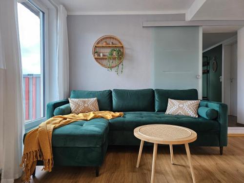 兰河畔马尔堡Tucan - Rooftop Terrace with View, BBQ, PS4+Stream的客厅配有一张绿色沙发,设有一张桌子