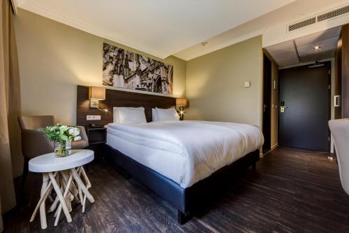 登博斯斯海尔托亨博斯弗莱彻餐厅酒店的酒店客房设有一张大床和一张桌子。