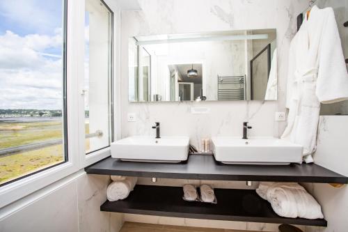 富埃南Logis Hôtel de la Pointe du Cap Coz的一间带两个盥洗盆的浴室和一个大窗户
