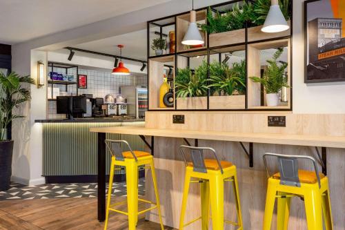 切斯特Super 8 by Wyndham Chester East的一间设有黄色凳子和植物台面的餐厅