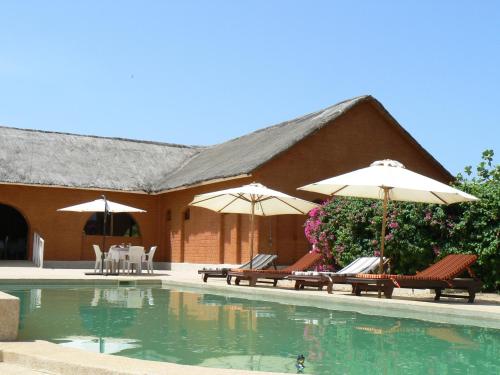 Fadial包巴山林小屋的一座带椅子和遮阳伞的游泳池位于一座建筑旁边