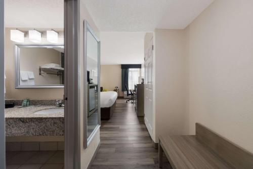 汉普顿贝斯特韦斯特汉普顿体育场酒店的走廊上设有一张床和镜子的酒店客房