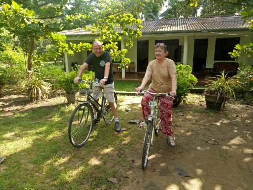 波隆纳鲁沃Deer Garden Guest的一名男子和一名女子骑着自行车在房子前