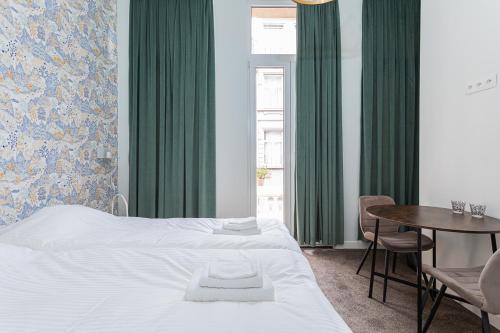 安特卫普Studio Anvers的一间卧室配有一张床、一张桌子和绿色窗帘