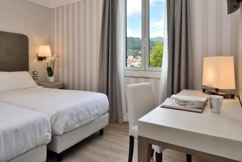 斯培西亚佛罗伦萨洲际酒店的配有一张床、一张书桌和一扇窗户的酒店客房