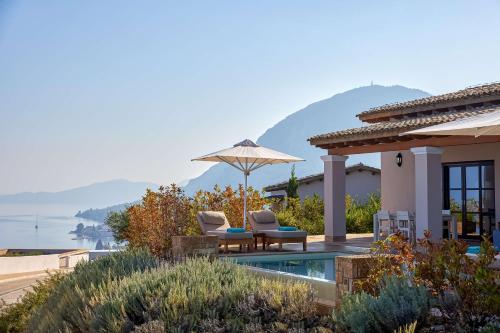 贝尼蔡斯Angsana Corfu Resort & Spa的一座房子,配有两把椅子和一把伞