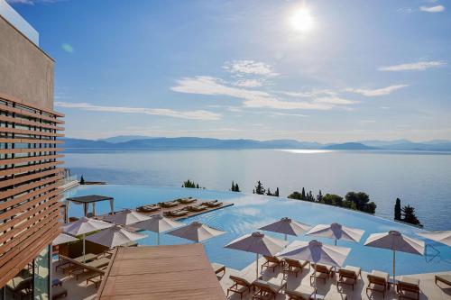 贝尼蔡斯Angsana Corfu Resort & Spa的一个带椅子和遮阳伞的大型游泳池