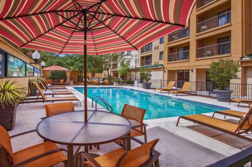查尔斯顿Courtyard by Marriott North Charleston Airport Coliseum的游泳池旁带遮阳伞的桌子