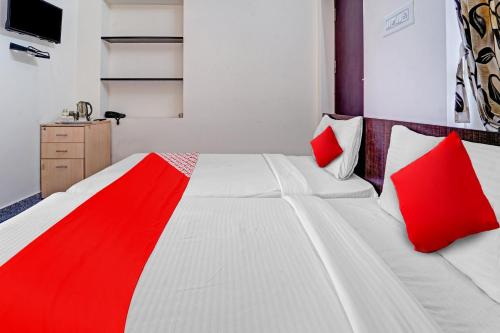 NāmakkalSuper OYO Flagship Royal Residency的一间卧室配有两张白色床和红色枕头