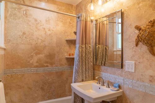基韦斯特Southernmost Point Guest House & Garden Bar的浴室配有盥洗盆、镜子和浴缸