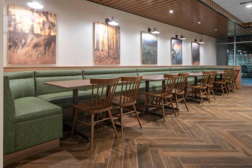 欧文达拉斯沃斯堡机场北/艾文费尔菲尔德客栈的餐厅设有桌椅,墙上挂有绘画作品