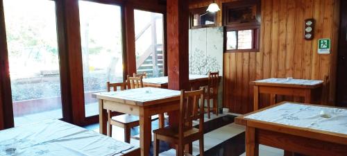 巴拉斯港Hostal Florencia的餐厅设有木桌、椅子和窗户