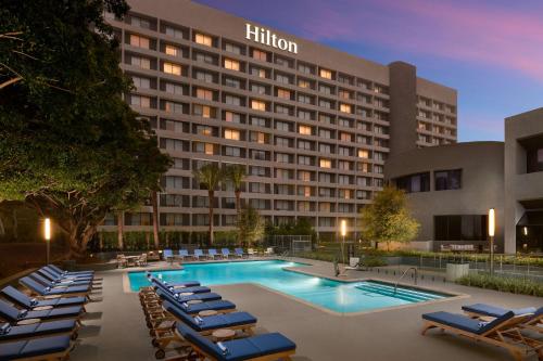 洛杉矶Hilton Los Angeles-Culver City, CA的酒店拥有游泳池和躺椅