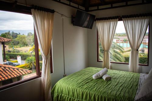 莱瓦镇El Pozzo Hotel Campestre的一间卧室设有一张绿色的床和一个大窗户