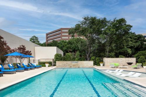 达拉斯达拉斯艾迪森科然姆商业街廊万豪酒店的一座带椅子的游泳池以及一座建筑