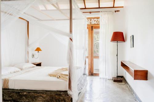 贝鲁沃勒Amuura Beach Villa的白色卧室配有一张带天蓬的床
