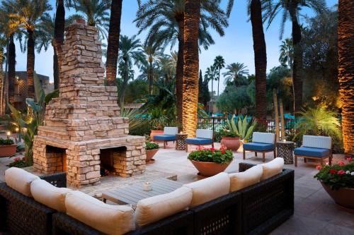 斯科茨斯科茨代尔希尔顿逸林度假酒店的庭院设有石制壁炉、椅子和棕榈树