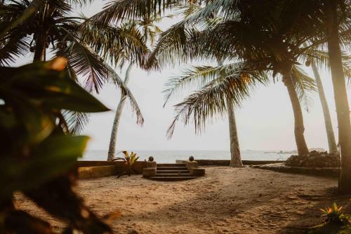 贝鲁沃勒Amuura Beach Villa的两人坐在棕榈树海滩上