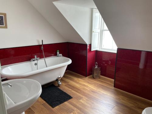 因弗雷里The Old Rectory的浴室配有白色浴缸和红色的墙壁。