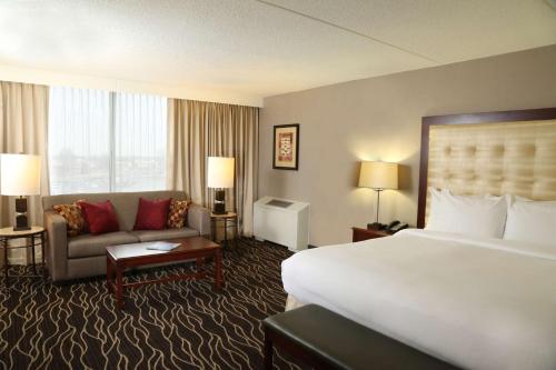 堪萨斯城希尔顿堪萨斯城机场酒店的酒店客房设有一张大床和一张沙发。