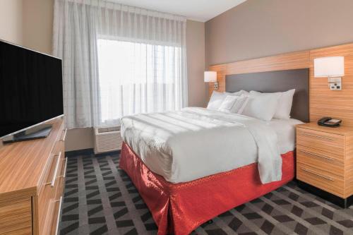 海斯Towneplace Suites By Marriott Hays的配有一张床和一台平面电视的酒店客房