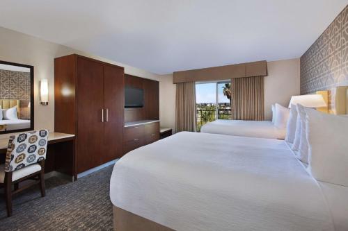 安纳海姆Embassy Suites by Hilton Anaheim North的酒店客房设有一张大床和一张书桌。