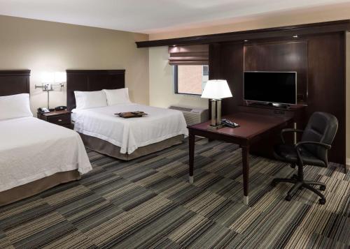 奥马哈奥马哈市中心汉普顿套房酒店的酒店客房设有两张床、一张桌子和一台电视。