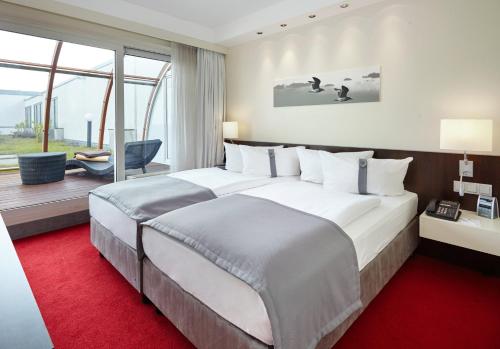 舍讷费尔德柏林机场-会议中心假日酒店的酒店客房配有一张大床和红地毯。
