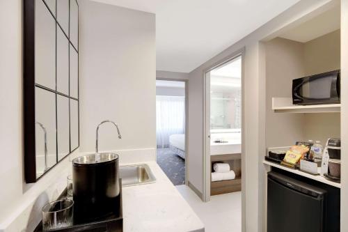 亚特兰大Embassy Suites by Hilton Atlanta Perimeter Center的带水槽的厨房和1间配有床的浴室