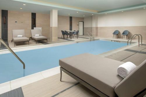 Dobbs Ferry多布斯费里威彻斯特希尔顿花园酒店的游泳池位于酒店客房内,配有床和椅子