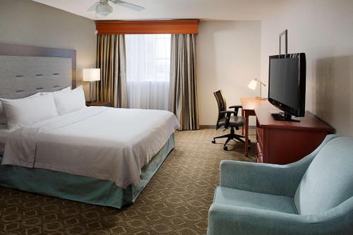 圣安东尼奥圣安东尼奥河滨/市区希尔顿惠庭套房酒店的酒店客房配有一张床、一张书桌和一台电视。