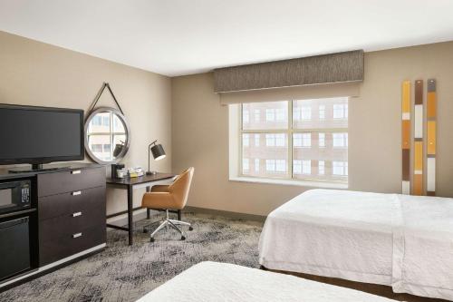 波特兰波特兰市中心水滨汉普顿酒店的酒店客房配有一张床、一张书桌和一台电视。